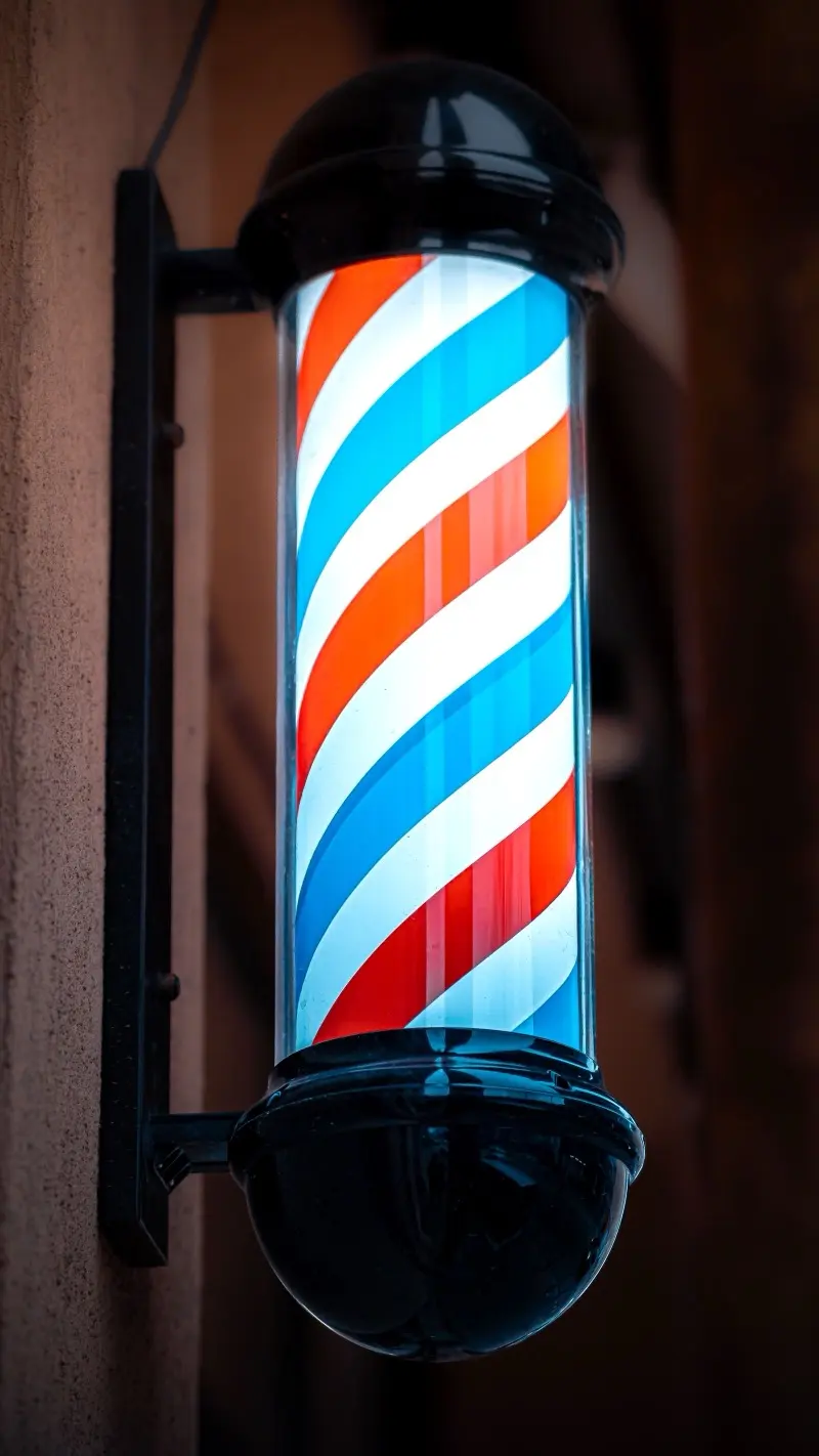 An illuminated barber pole glowing at dusk
